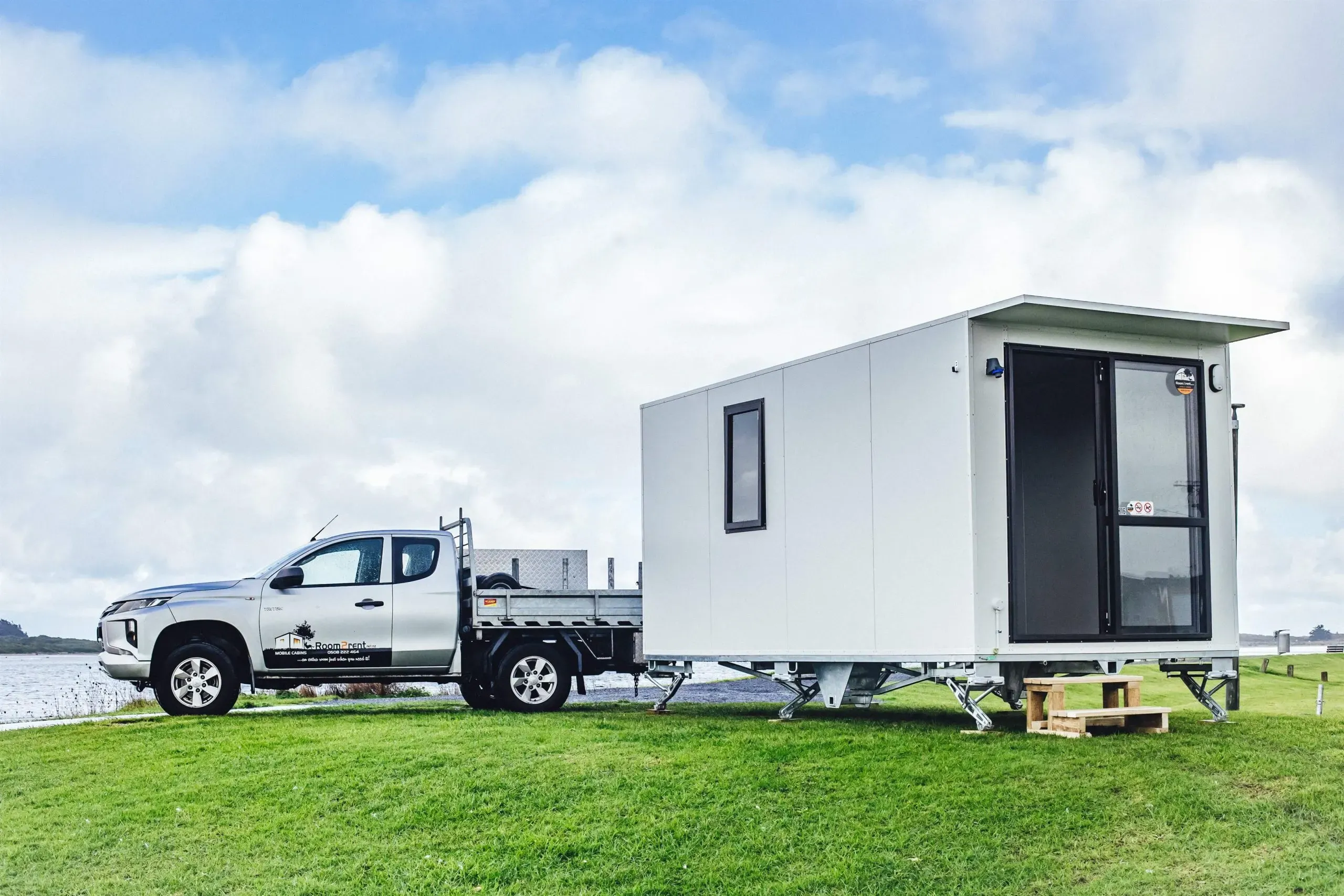 A white truck towing a small white house down a road, showcasing a unique mobile living situation1