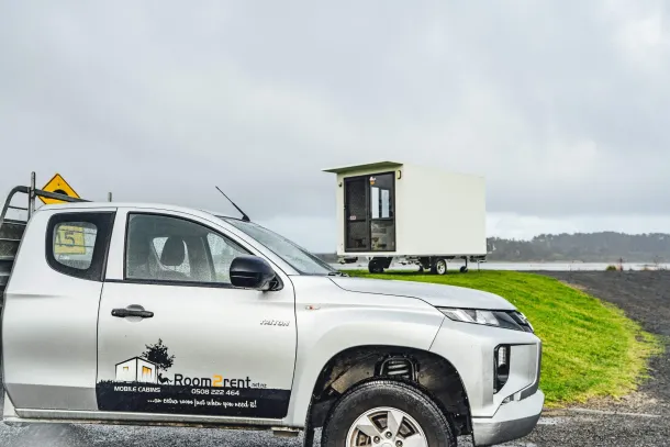 A large truck with a trailer is parked along the road, with a clear view of the surrounding landscape - right portable cabin