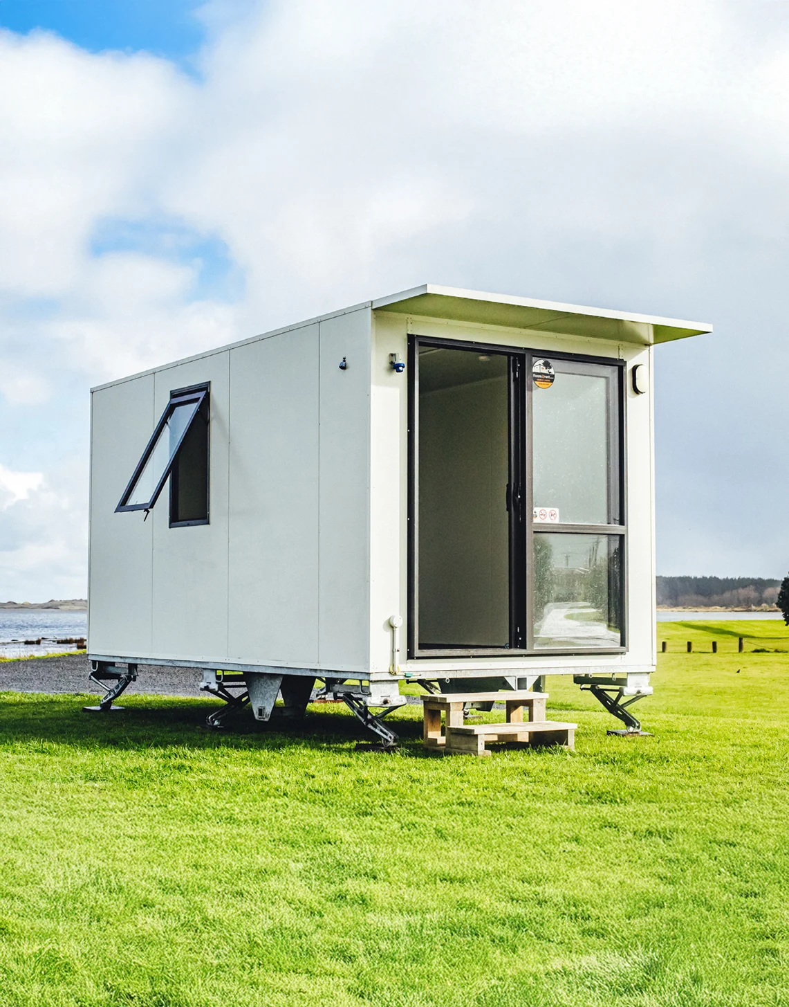 compact white mobile home rests atop a vibrant grassy field, with no other structures nearby