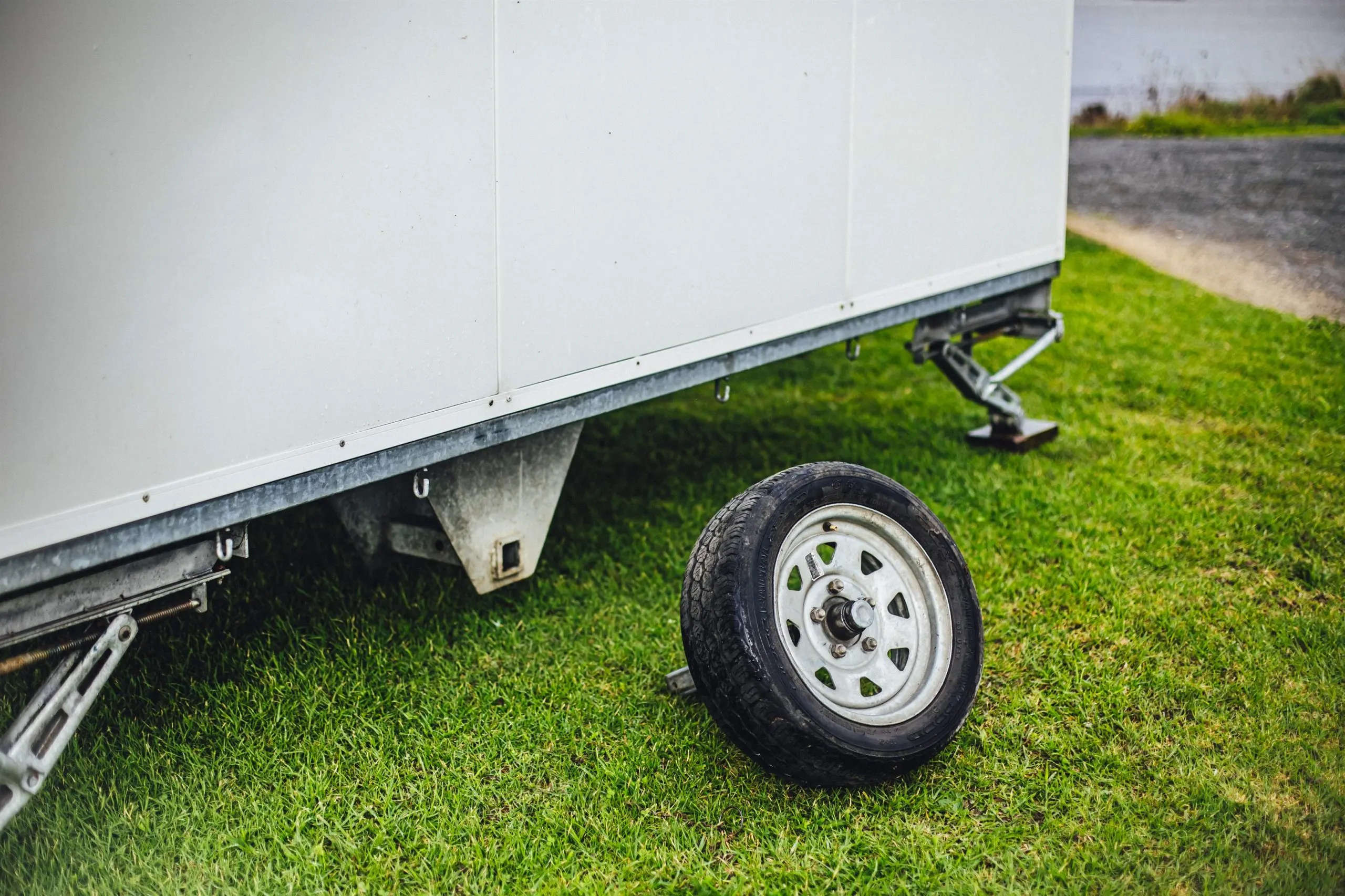 A trailer tire resting on green grass under natural light