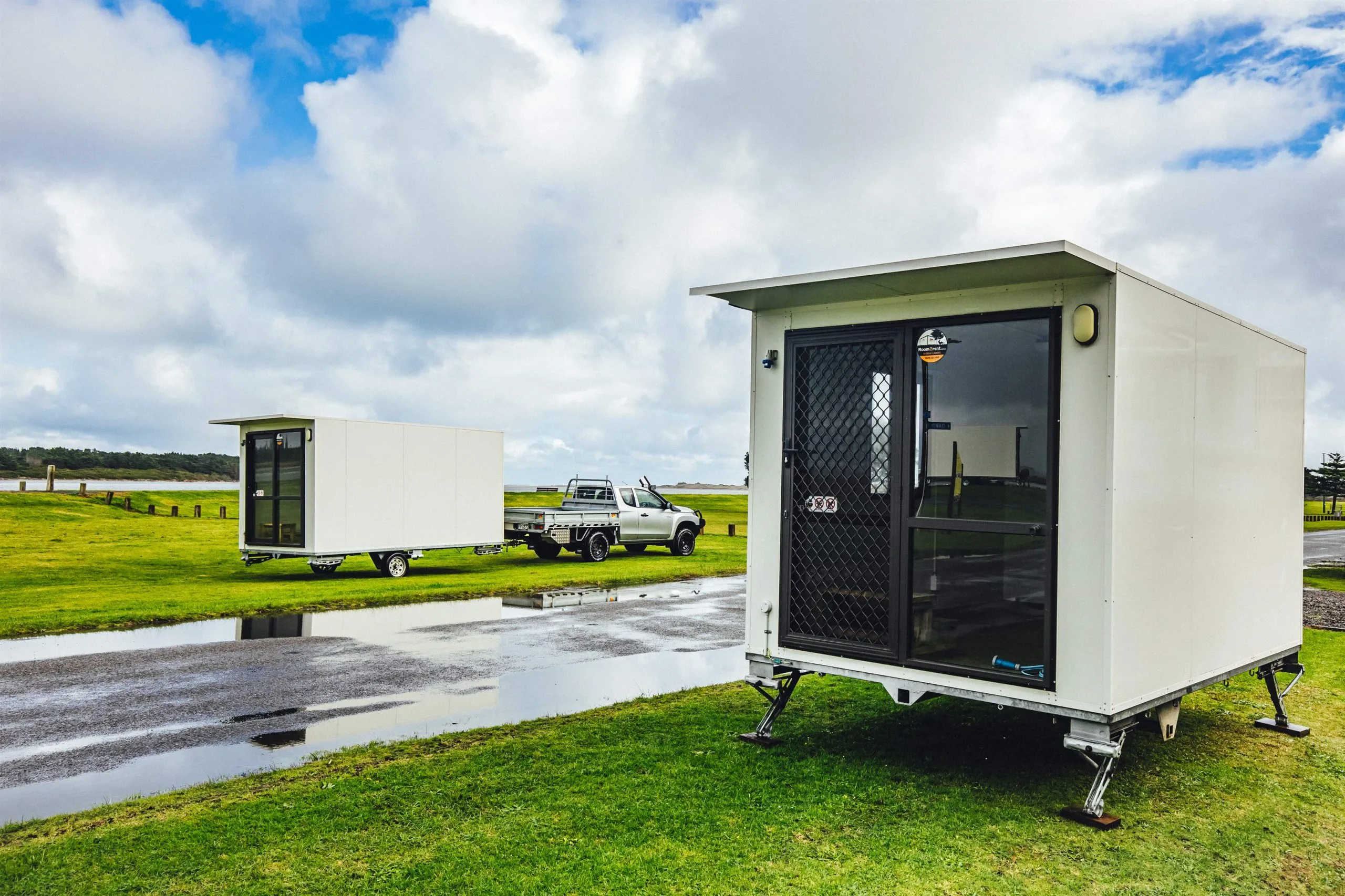 Two white mobile homes nestled on a grassy area, surrounded by nature