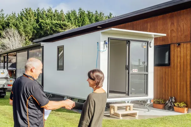 A man and woman are standing side by side in front of a mobile home