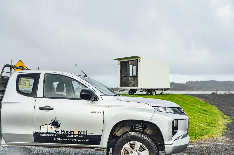 A large truck with a trailer is parked along the road, with a clear view of the surrounding landscape - right portable cabin